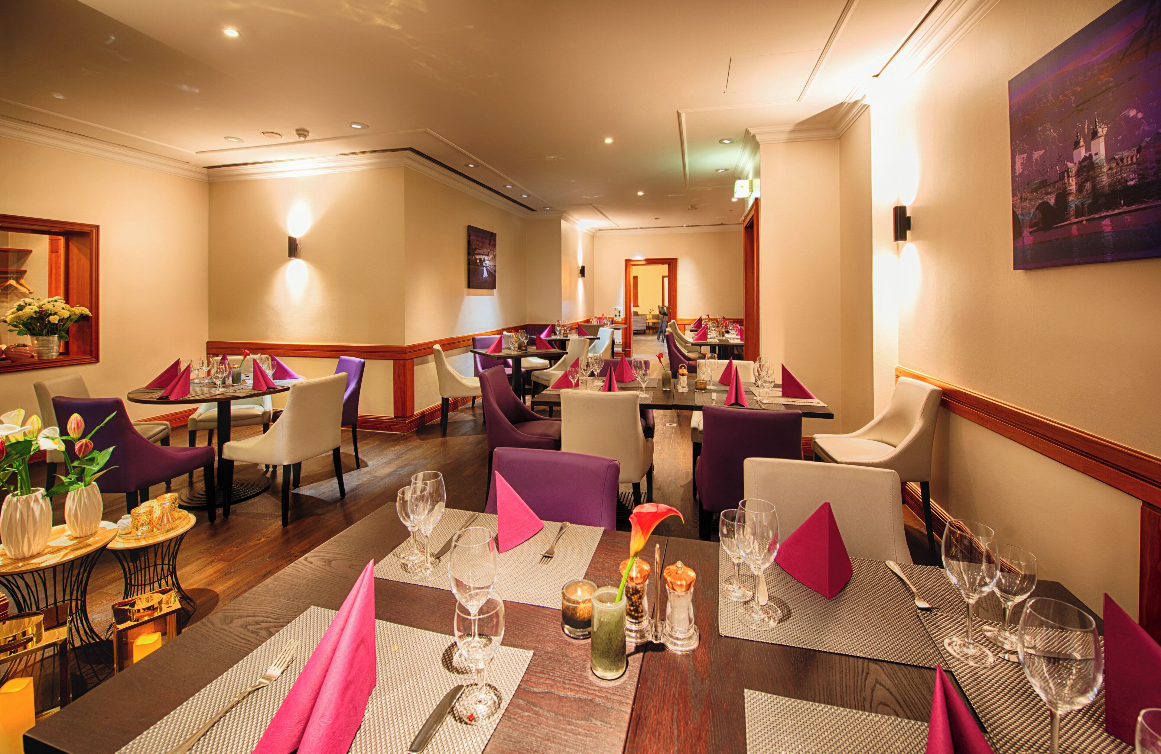 A restaurant with multiple tables set for dining, featuring a variety of chairs and table settings.