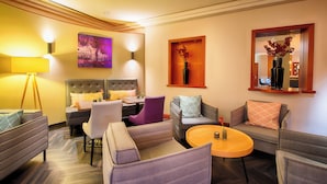 A modern hotel room with a sofa set, a small table, a decorative vase, and a painting on the wall. - Leonardo Hotel Heidelberg (Heidelberg)