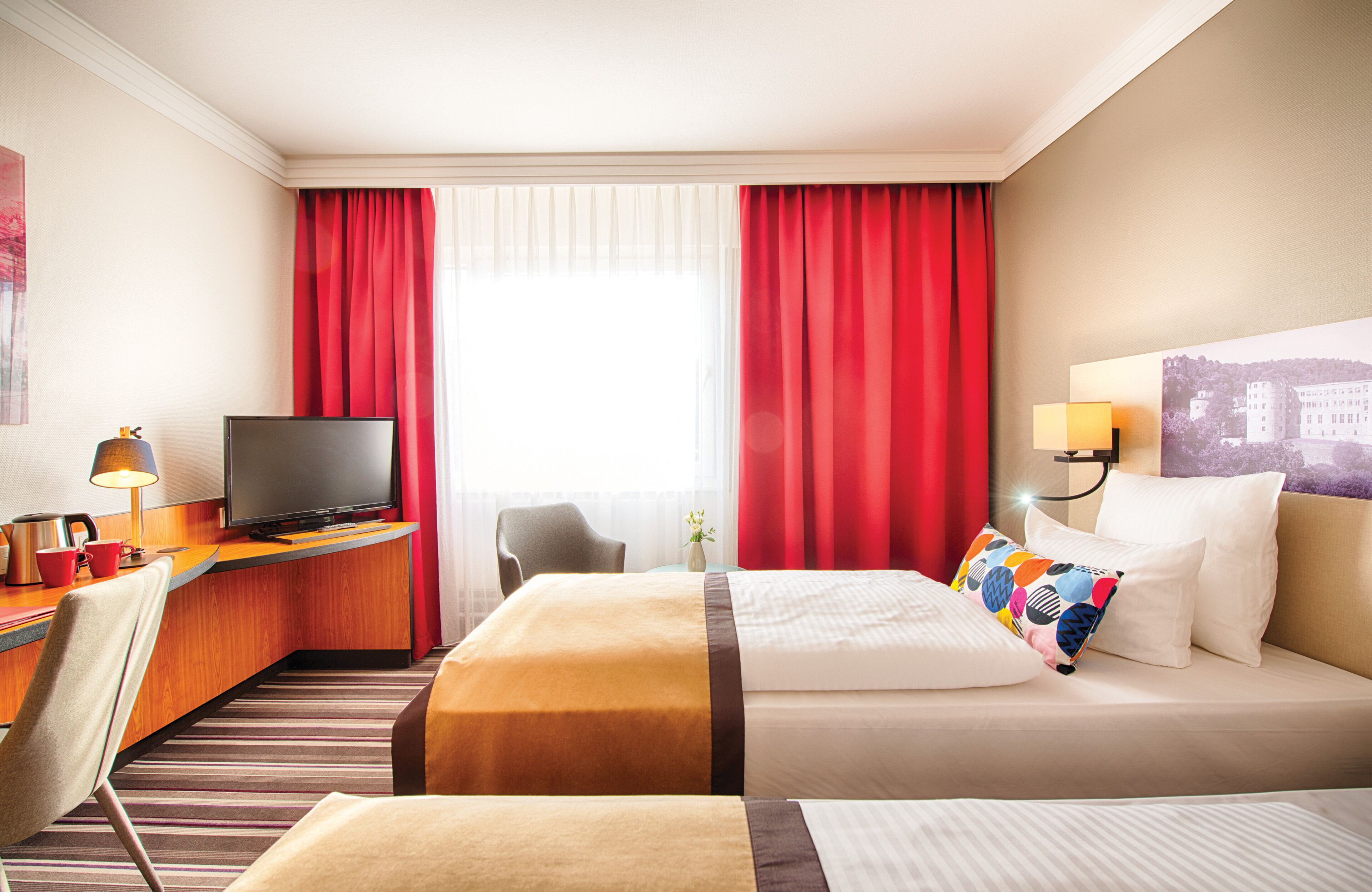 Une chambre d’hôtel comprenant un lit, un bureau avec une télévision, une chaise et une lampe.