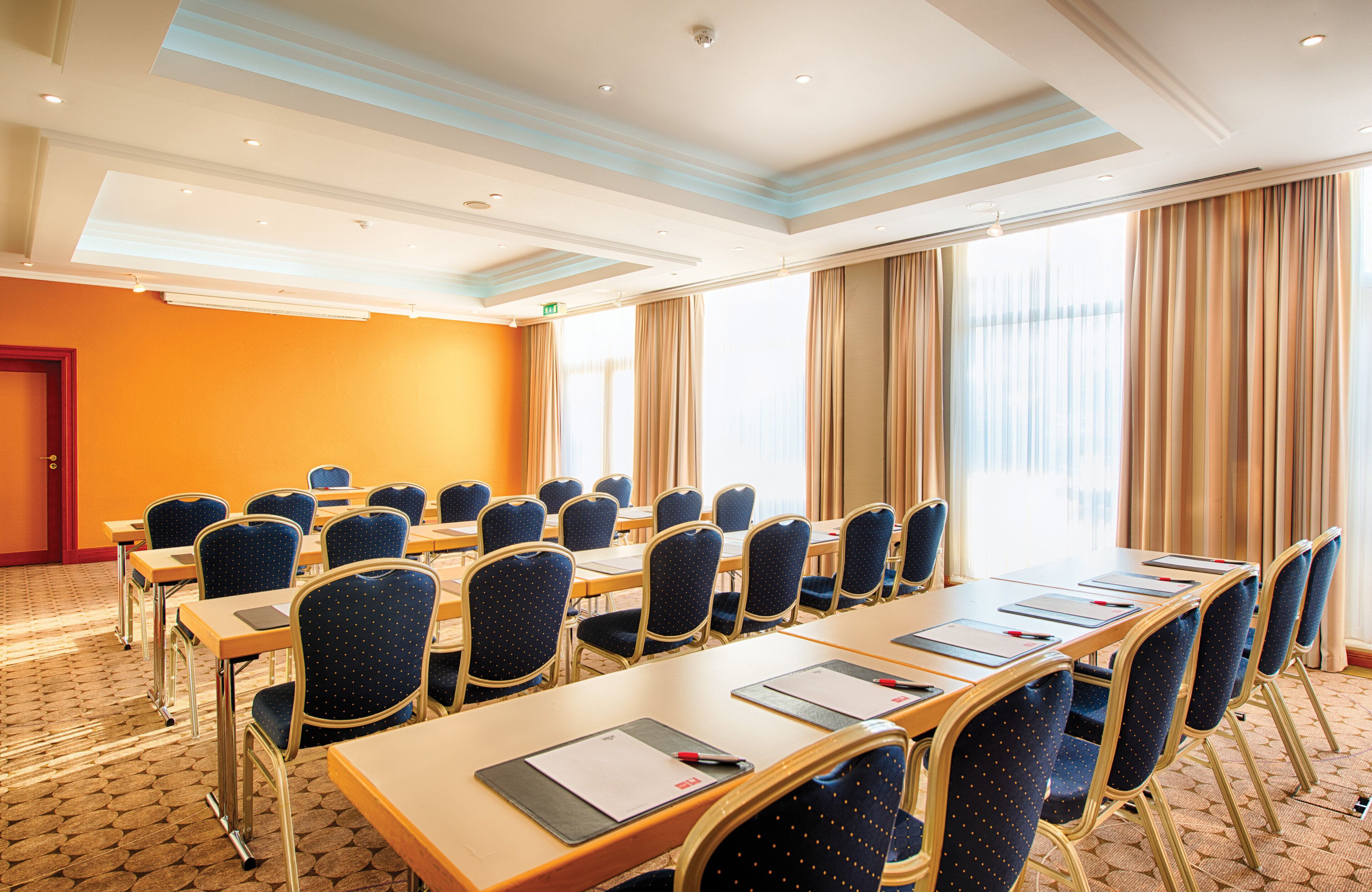 Une salle de conférence avec une longue table, des chaises et un sol recouvert de moquette.