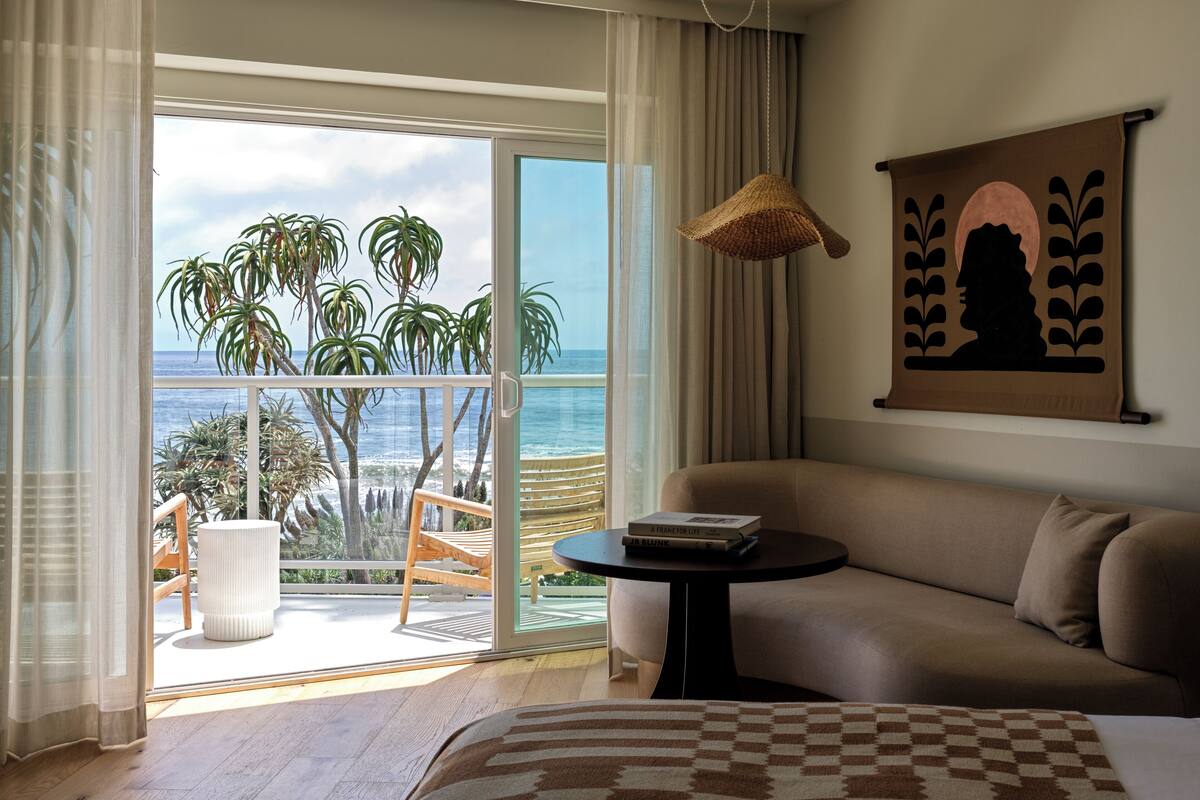 A room with a balcony, a sofa, a table, and a painting.