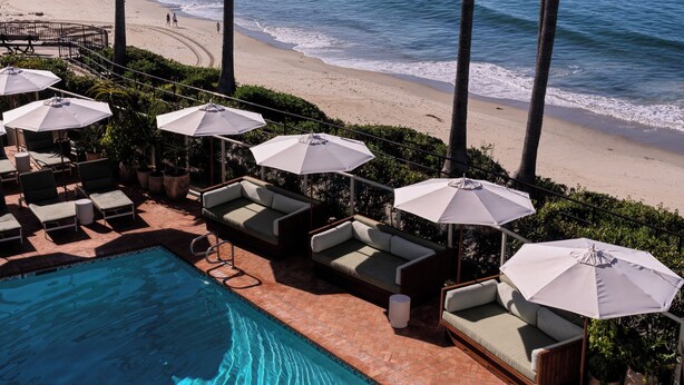 A poolside area with lounge chairs and umbrellas, overlooking a beach and ocean. - Casa Loma Beach Hotel (formerly The Inn at Laguna Beach) (Laguna Beach)
