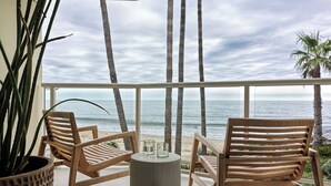 A balcony with two wooden chairs, a small table, and a potted plant. - Casa Loma Beach Hotel (formerly The Inn at Laguna Beach) (Laguna Beach)