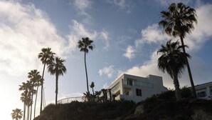 A modern building with a flat roof and large windows, surrounded by palm trees on a rocky hillside. - Casa Loma Beach Hotel (formerly The Inn at Laguna Beach) (Laguna Beach)