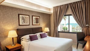 A hotel room with a large bed, two bedside lamps, a chair, and a desk. - Sheraton Riyadh Hotel & Towers (Riyadh)