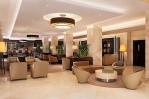 A spacious lobby with modern furniture, a central coffee table, and ambient lighting.