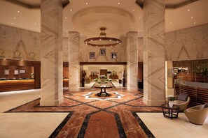 A hotel lobby with marble columns, a reception desk, a central floral arrangement, and a modern chandelier. - Sheraton Riyadh Hotel & Towers (Riyadh)