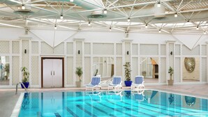 A swimming pool with clear blue water, surrounded by white lounge chairs and potted plants. - Sheraton Riyadh Hotel & Towers (Riyadh)