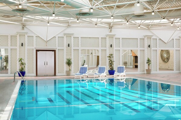 A swimming pool with clear blue water, surrounded by white lounge chairs and potted plants. - Sheraton Riyadh Hotel & Towers (Riyadh)