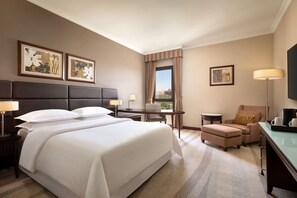 A hotel room with a large bed, a desk, a chair, and a television.