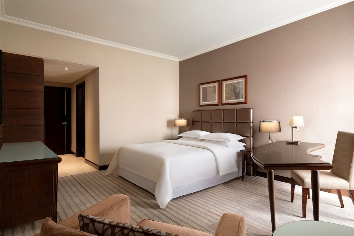 A hotel room with a bed, bedside tables, a desk, and a chair.