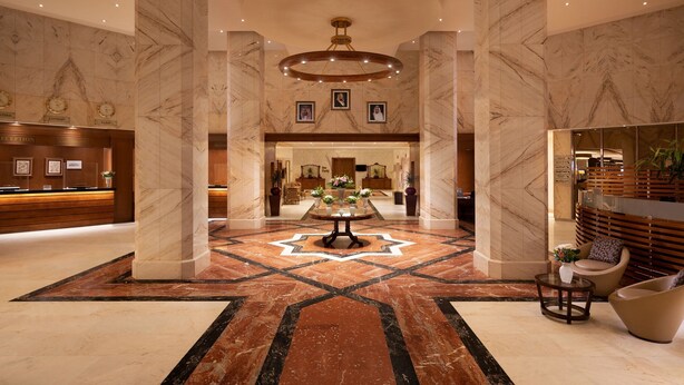 A spacious lobby with marble columns, a central table with flowers, and a reception desk. - Sheraton Riyadh Hotel & Towers (Riyadh)