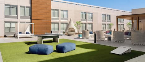 An outdoor patio with artificial grass, seating areas, and a pool table.
