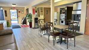 A hotel lobby with a dining area, a refrigerator, a staircase, and a plant. - Econo Lodge Lansing - Leavenworth (Lansing)