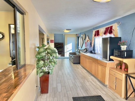 A modern kitchen with wooden cabinets, a built-in microwave, and a potted plant.