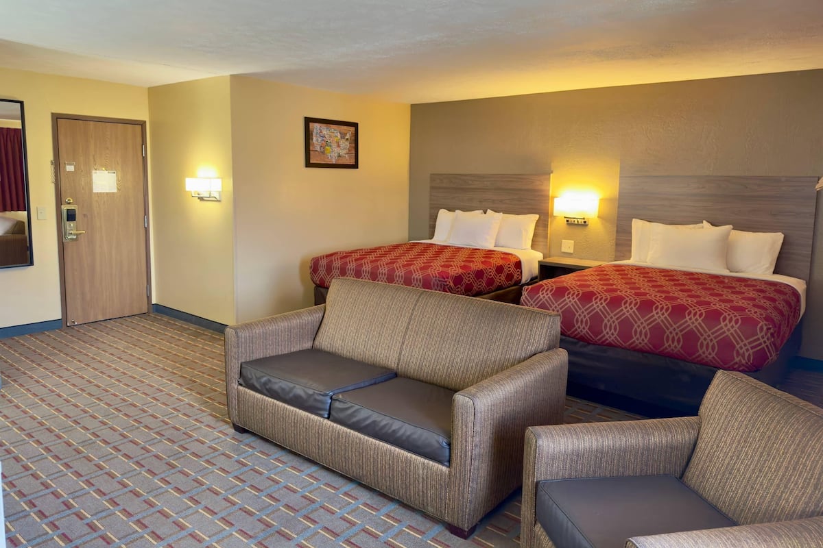 Une chambre d’hôtel avec deux lits, un canapé et une petite table.