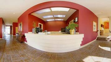 A reception area with a curved white reception desk, red walls, and a tiled floor.