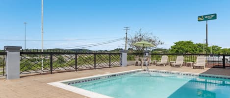 Un espace piscine avec des chaises longues, une clôture et un panneau indiquant « Quality Inn ».