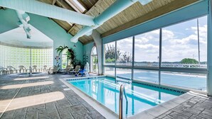 An indoor swimming pool with a view of the sea, a tiled floor, and a ceiling with exposed beams. - Quality Inn London North (London)