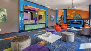 A modern hotel lobby with colorful walls, seating areas, and a bar. - Quality Inn London North (London)