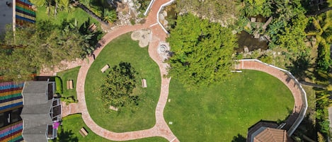 Vista aérea de un jardín con senderos, un estanque pequeño y zonas ajardinadas.