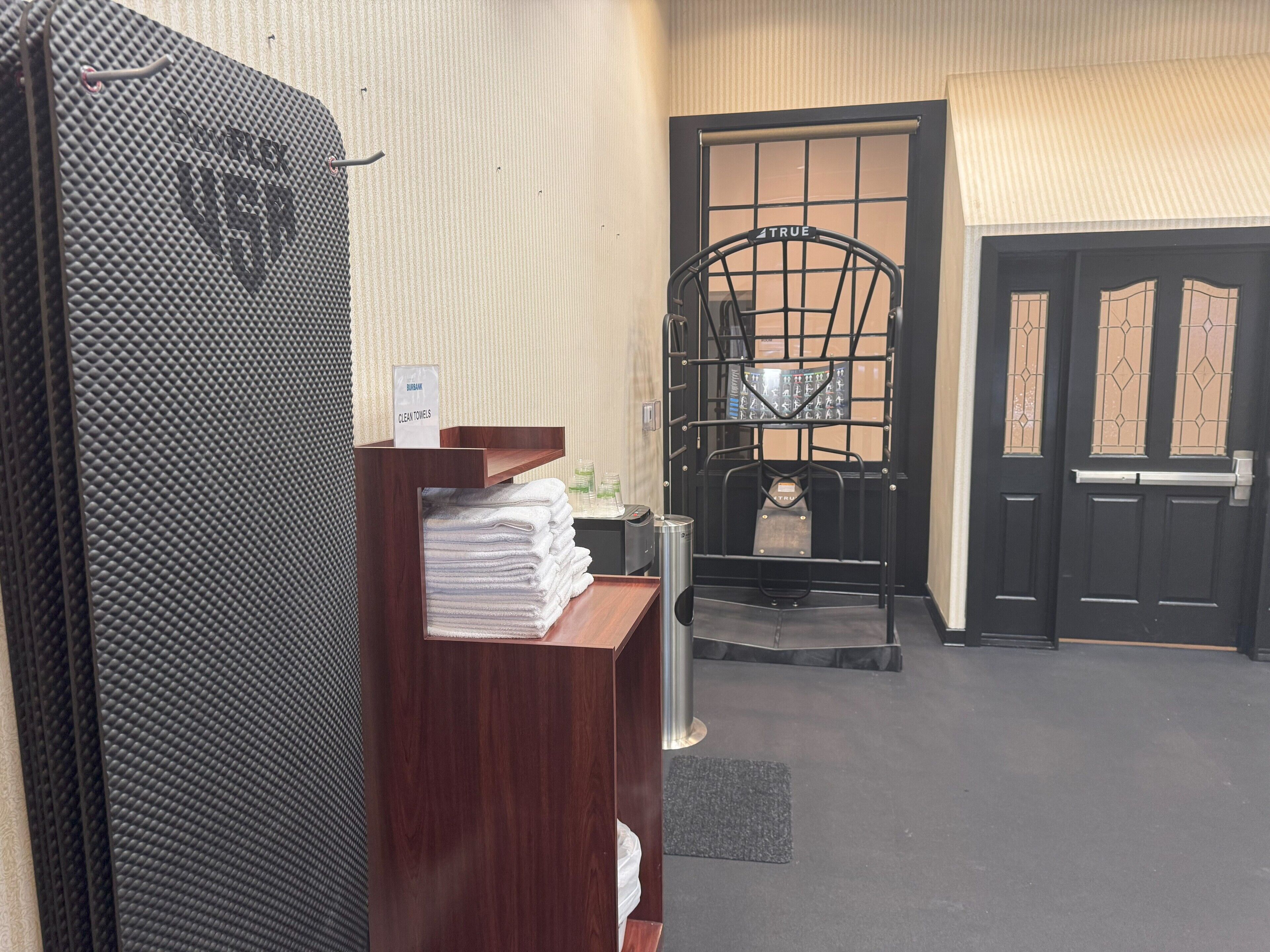 Zona de recepción con mostrador, una silla de metal negro y una puerta con ventanal.