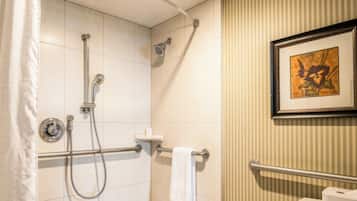 Un baño con ducha, inodoro y un cuadro en la pared.