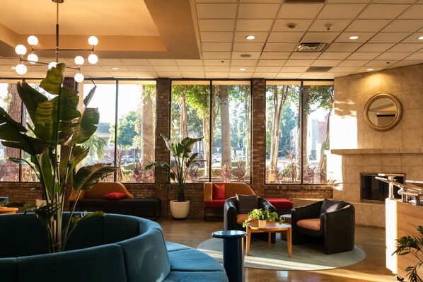 A modern lobby with a blue sofa, a wooden coffee table, and a fireplace. - Hotel Burbank (Burbank)