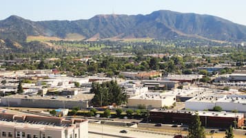 A cityscape with a mountain range in the background, a highway with vehicles, and buildings with flat roofs.