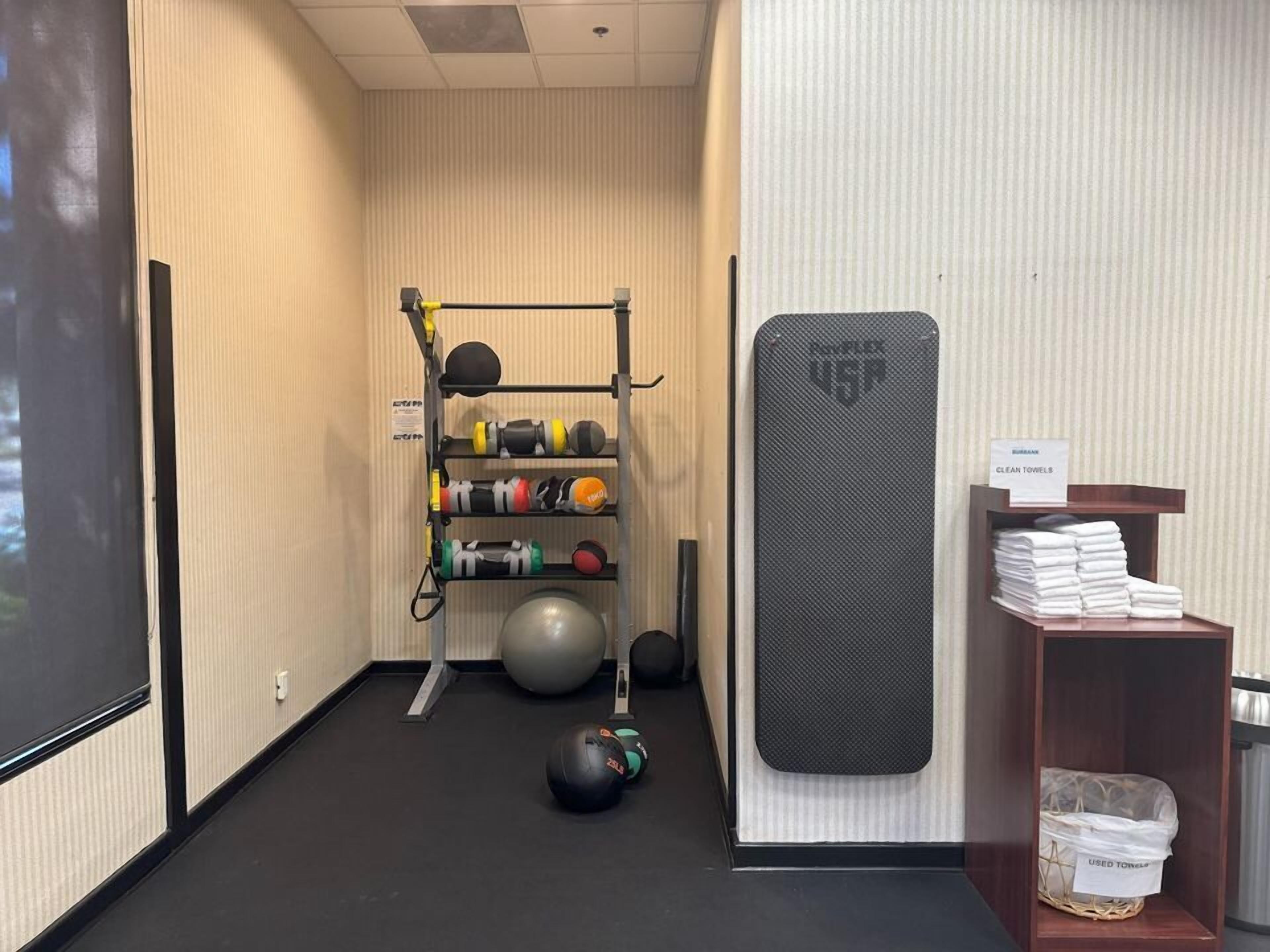 Ein Fitnessbereich mit Trainingsgeräten, einer Klimmzugstange und einem Ablageschrank mit Handtüchern.