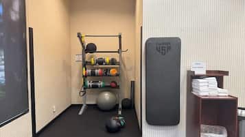 A gym area with exercise equipment, a pull-up bar, and a storage shelf with towels.