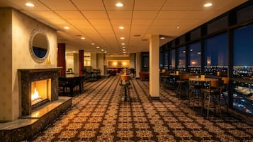 A hotel lobby with a fireplace, patterned carpet, and a bar area with seating.