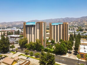 Two Hotel Burbank buildings with a clear view of the surrounding urban landscape and mountains in the background. - Hotel Burbank (Burbank)