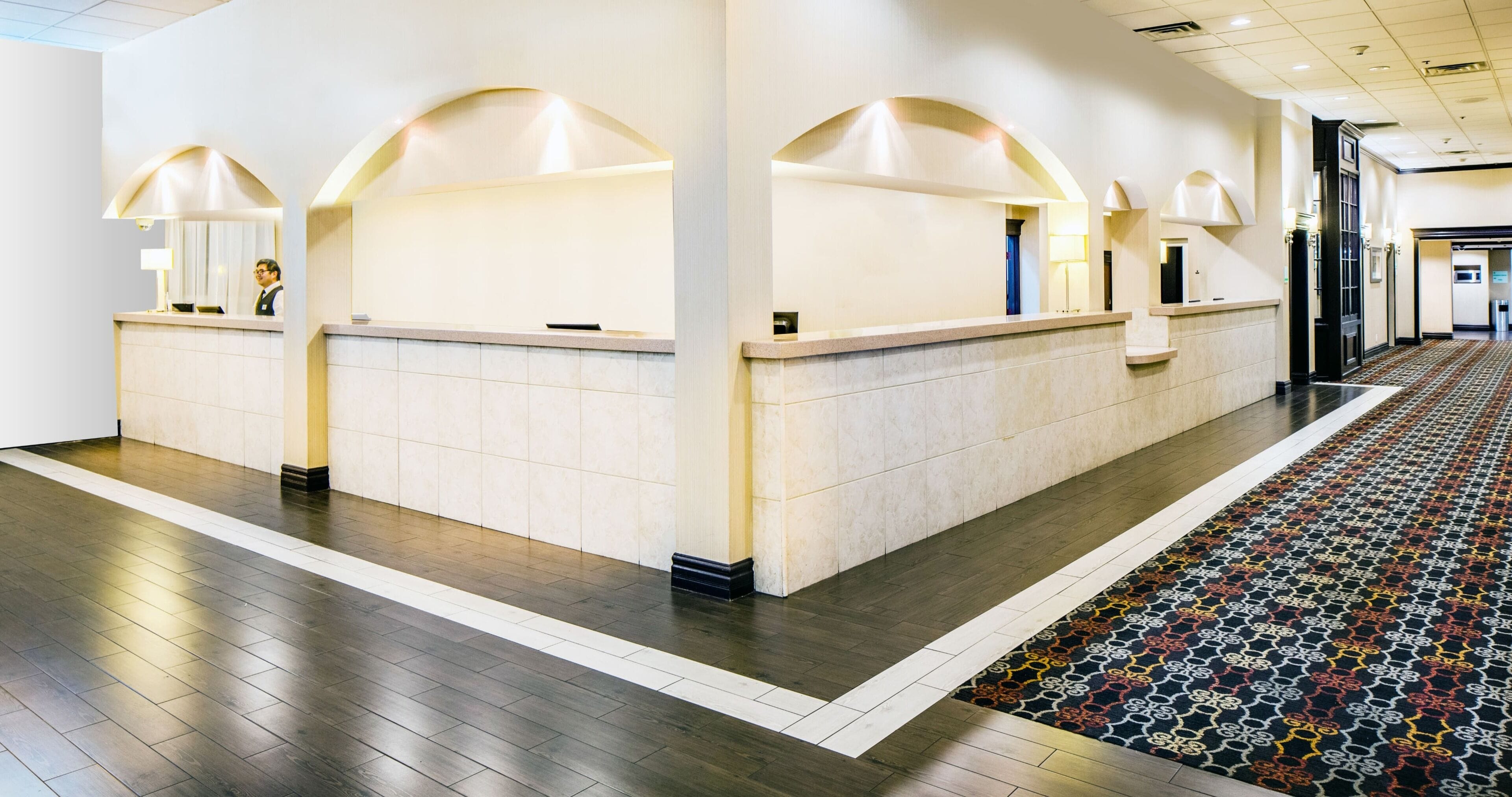 A reception area with a marble counter, a patterned carpet, and a modern interior design.