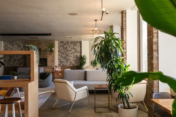 A modern living room with a sofa, chairs, a coffee table, and potted plants. - Hotel Burbank (Burbank)