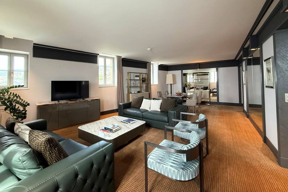A modern living room with a flat-screen TV, leather sofas, a coffee table, and striped chairs.