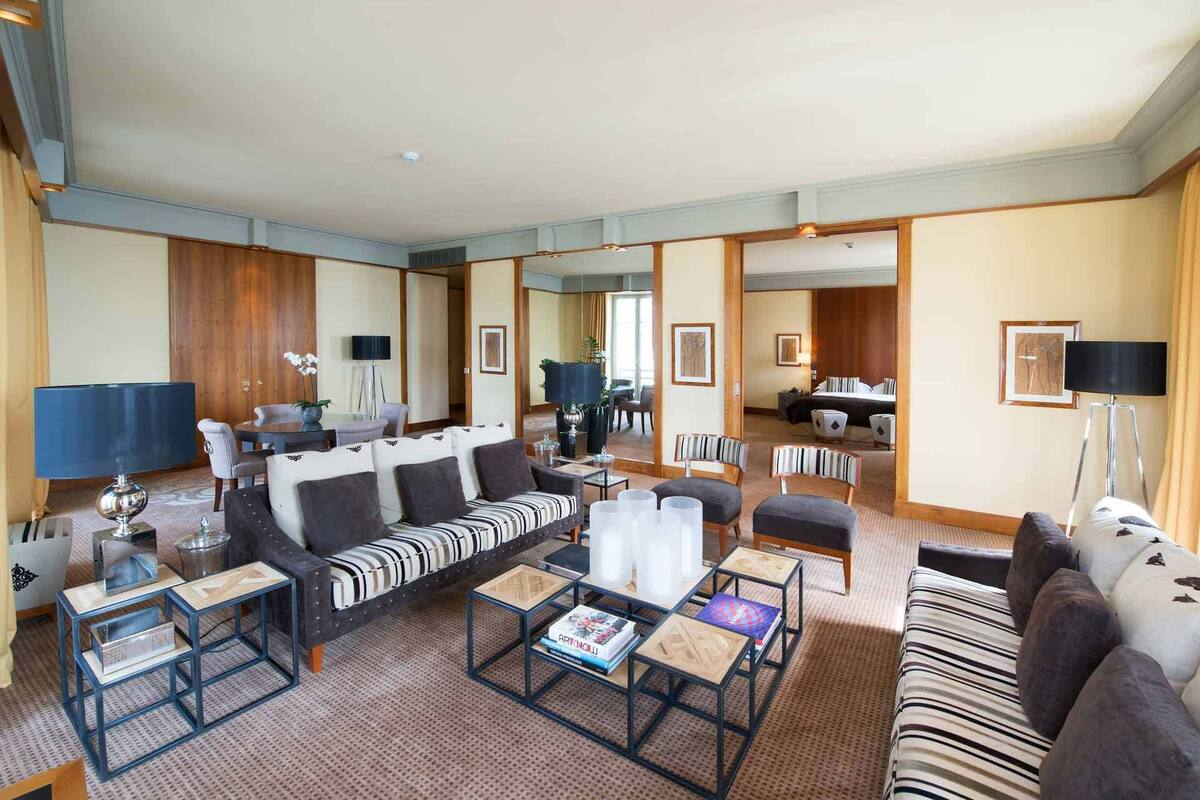 A spacious living room with a sofa set, coffee tables, and a TV.