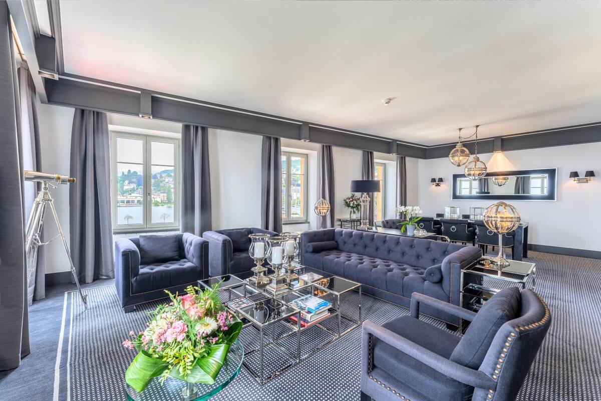 A modern living room with a sectional sofa, a glass coffee table, and a seating area with a small table and lamp.