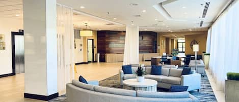 A spacious lobby with a curved sofa, a round coffee table, and a seating area with multiple chairs.