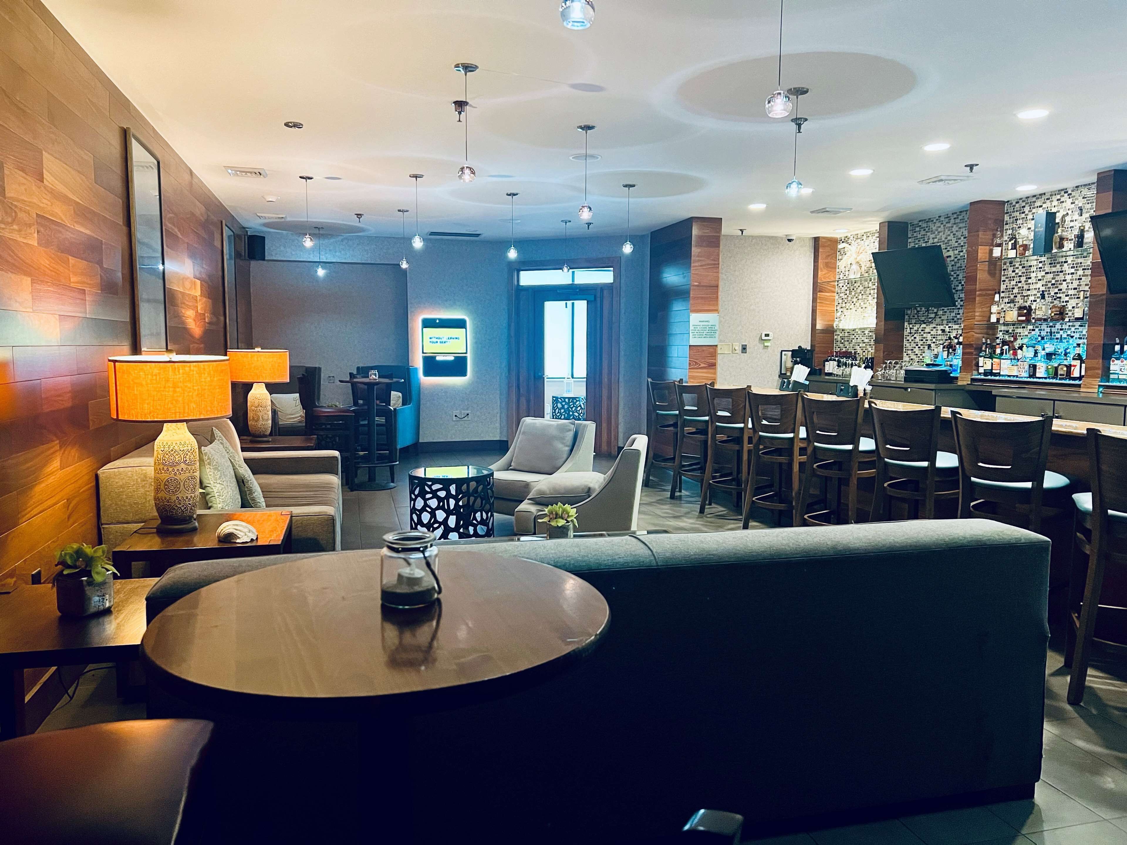 Un moderno vestíbulo de hotel con zona de bar, asientos y mostrador de recepción.