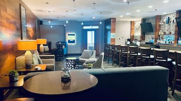 A modern hotel lobby with a bar area, seating arrangements, and a reception desk.