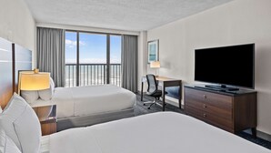 Habitación de hotel con dos camas, un escritorio, un televisor, una silla y una ventana con cortinas.