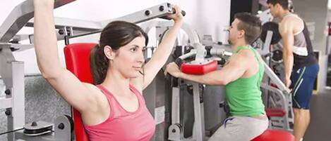 A gym with exercise equipment, including a seated row machine and a bench press.