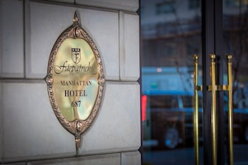 A man in a suit standing next to a sign for the Manhattan Hotel 687. at Fitzpatrick Manhattan Hotel