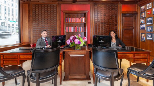 Una oficina moderna con dos escritorios, sillas, una estantería y un florero.