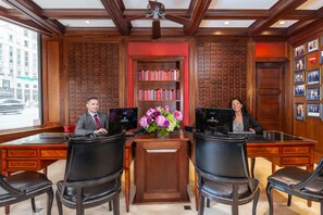 Un bureau professionnel équipé de deux bureaux, de chaises, d’une bibliothèque et d’un vase de fleurs.