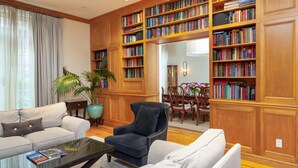 Una sala de estar con un sofá, un sillón y una mesa de centro, rodeada de estanterías de madera llenas de libros.