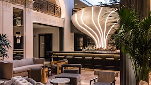 Un vestíbulo moderno con área de bar, asientos y una iluminación decorativa.