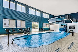 An indoor swimming pool with a slide, clear signage, and a view of the outside. - Baymont by Wyndham Bozeman (Bozeman)