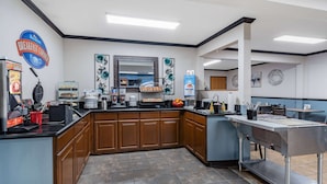 A breakfast area with a counter, coffee machine, and various food items. - Baymont by Wyndham Bozeman (Bozeman)